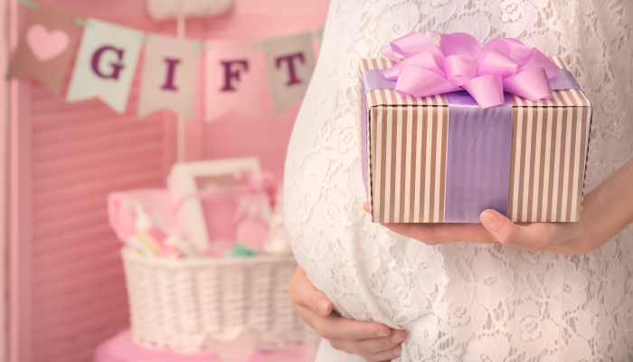 Pregnant woman holding gift at baby shower party