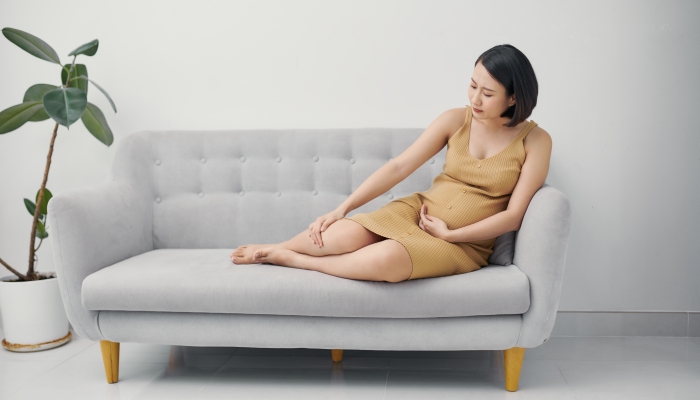 Pregnant woman massaging a swollen foot.