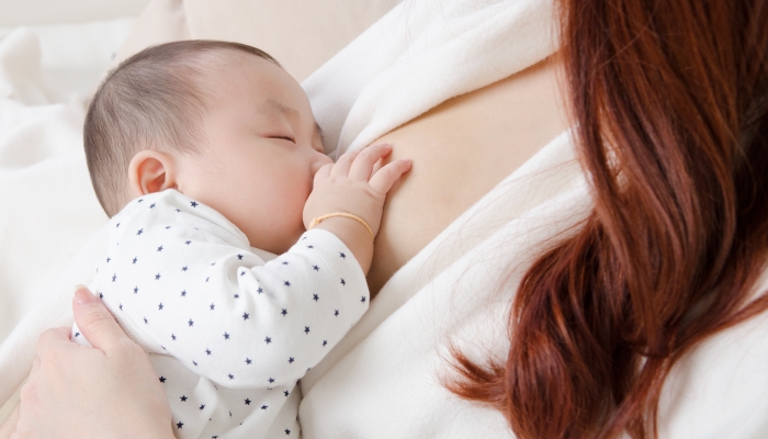 Six months old asian baby drinking breastmilk.