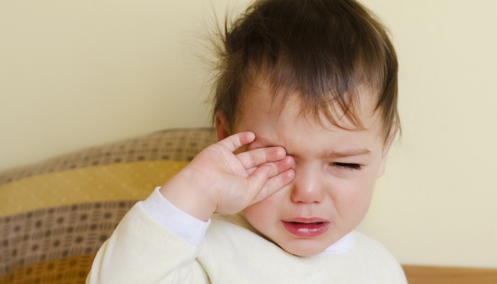 Sleepy toddler child crying in a bed after waking up or before going to sleep