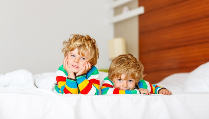 Two little sibling kid boys having fun in bed after sleeping at home.