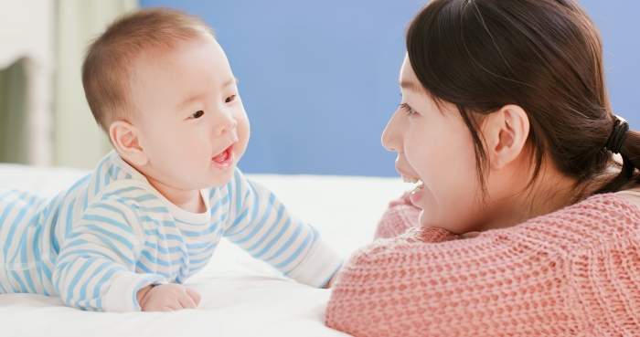 asian mother play with her baby on the bed.