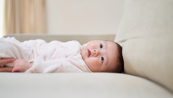 Asian baby lying on the couch.