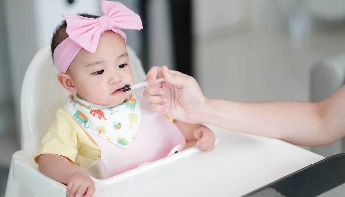Asian cute baby girl taking a gripe water after a meal.