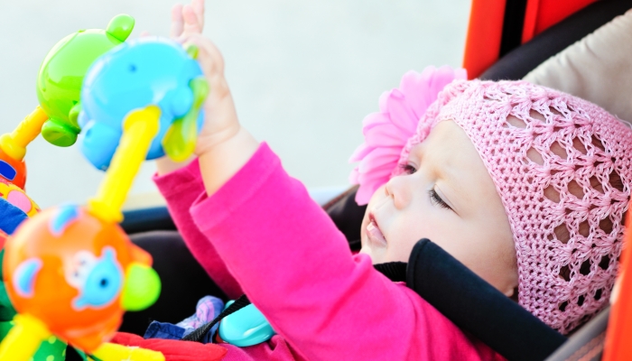 Baby in stroller playing toys.