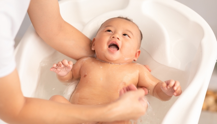 Calm of asian newborn baby bathing in bathtub.
