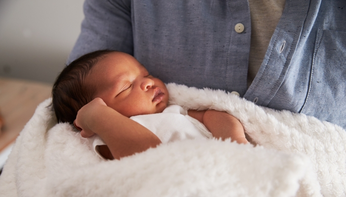 Close Up Of Father Holding Newborn Baby Son In Nursery.