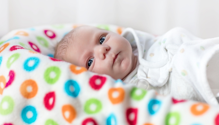 Cute little newborn baby girl wrapped in blanket.