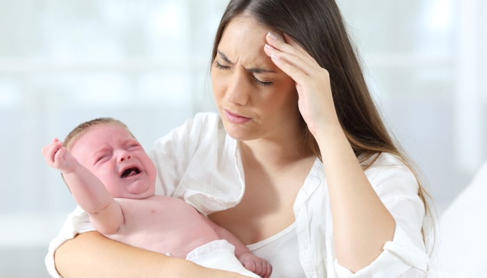 Desperate mother holding her angry baby crying.