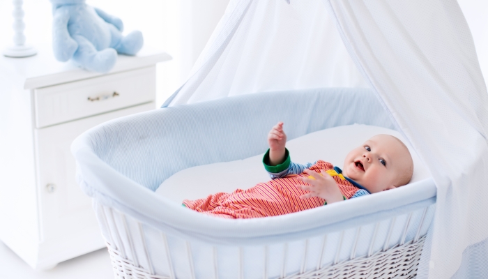 Funny baby in white crib with canopy.