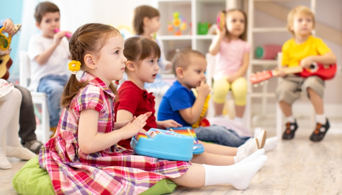 Group of kids 3-4 years old with toy musical instruments.