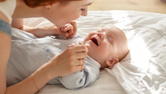 Happy young mother bonding with her toddler son in blue sleeping suit.