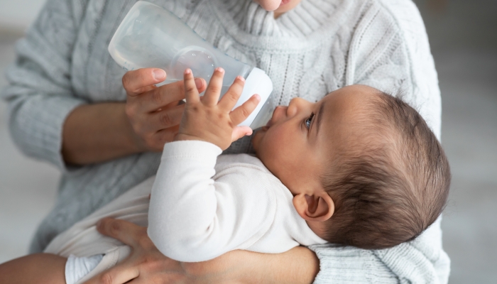 Kid wearing bodysuit while drinking gripe water.