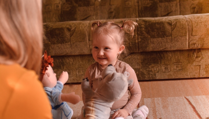 Little girl plays puppet theater with his mother at home, selective focus, noise effect.