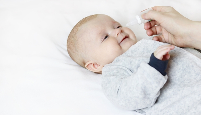 Mother drips drops to cure the sick baby.