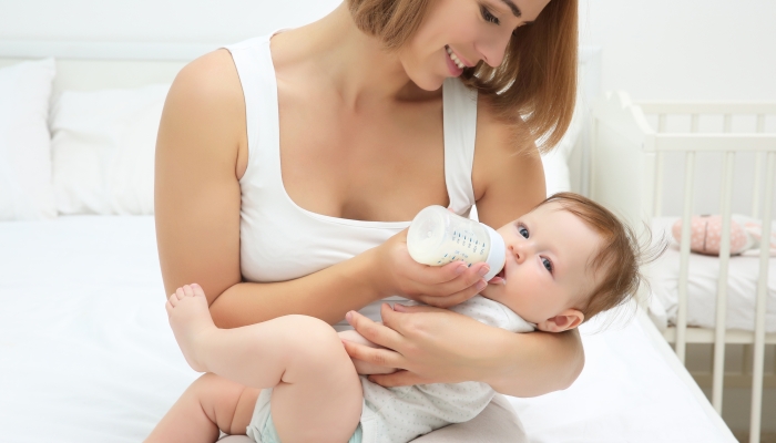 Mother holding and feeding baby from bottle.