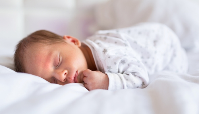 Newborn baby boy sleeping in bed.