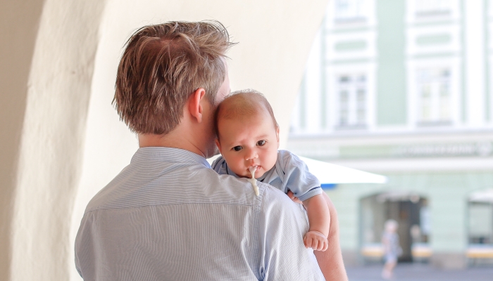 Newborn boy vomiting while his dad carrying him on outdoor.