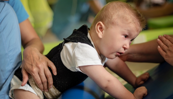 Portrait of a baby with cerebral palsy on physiotherapy in a children therapy center.