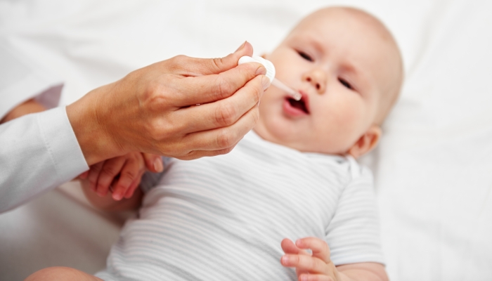 Portrait of baby girl getting vaccine drops.