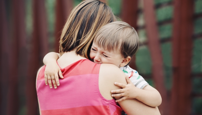 Portrait of young Caucasian woman mother comforting her crying little toddler boy.