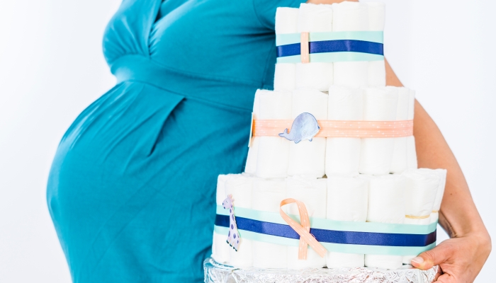 Pregnant woman holding diaper cake for her unborn boy.