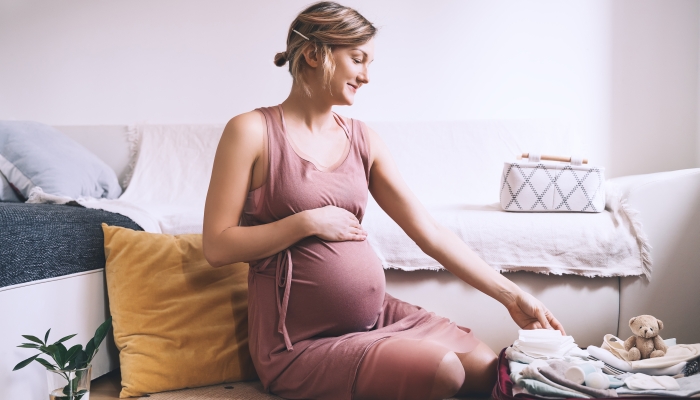 Pregnant woman packing bag for maternity hospital, making notes, checking list in diary.