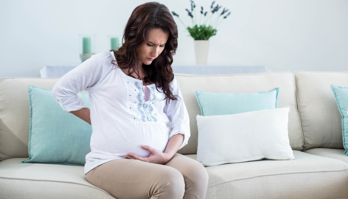 Pregnant woman with painful back in living room.