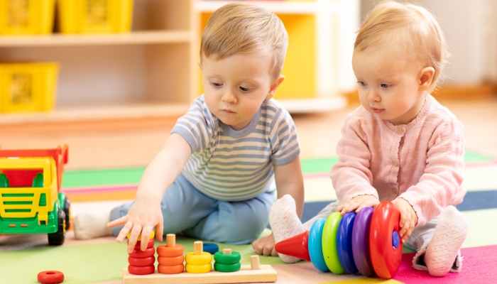 Preschool boy and girl playing on floor with educational toys.
