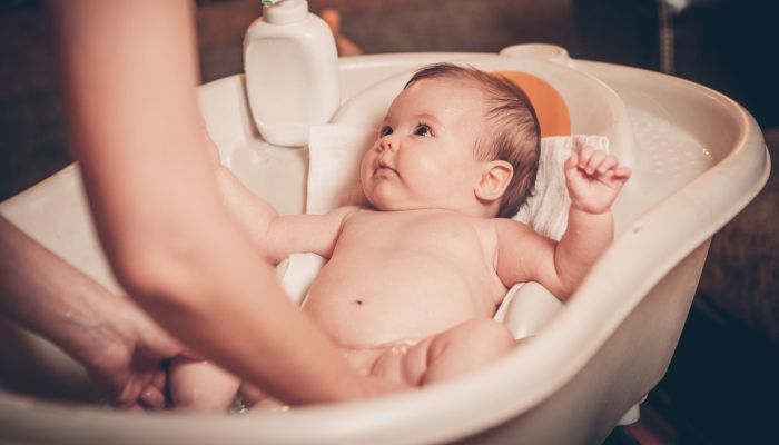 Small baby first bathing on mothers hands.