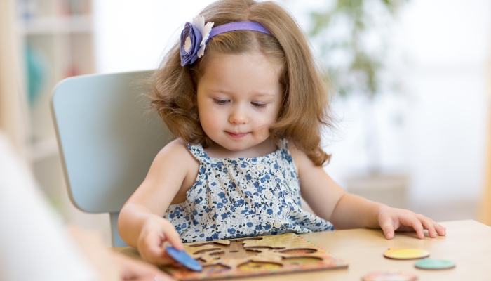 Small toddler or baby kid playing with puzzle shapes.