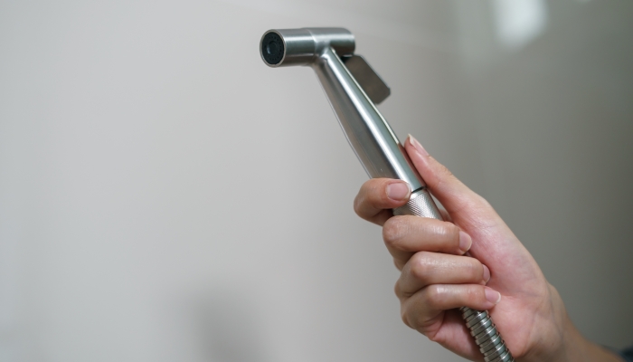 Woman hand using Chromium bidet shower.