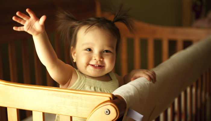 Baby girl in wood crib.