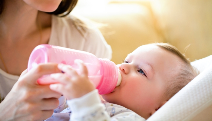 happy mother feeds the baby bottle.