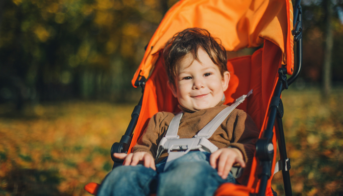 Little boy in orange umbrella stroller.