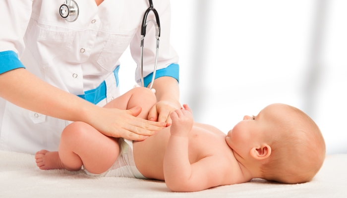 A Doctor examines and massaging baby tummy.