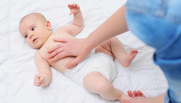 A caring mother gives her baby son a tummy massage and helps to get rid of colic.