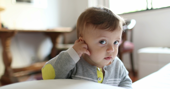 Adorable baby playing with ear.