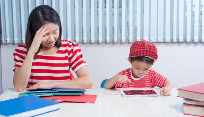 Asian boy playing tablet and his mother frustrated.