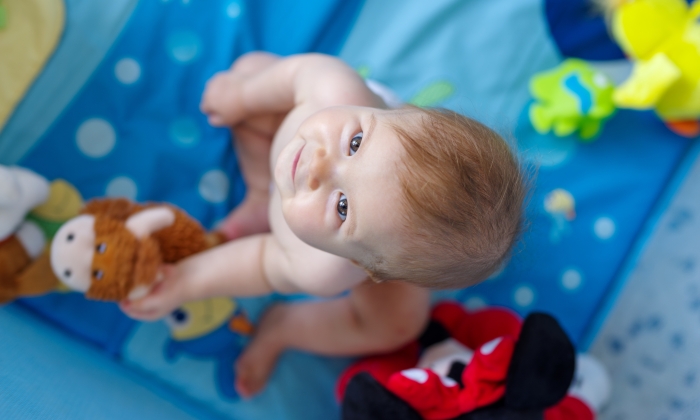 Baby girl in playpen looking up.