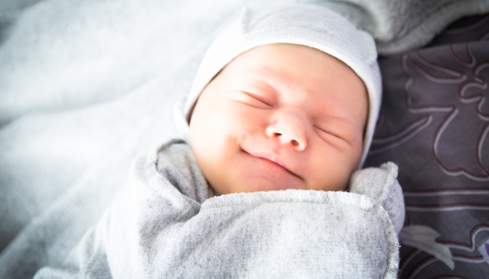 Beautiful newborn sweetly sleeps in the crib and has beautiful dreams.