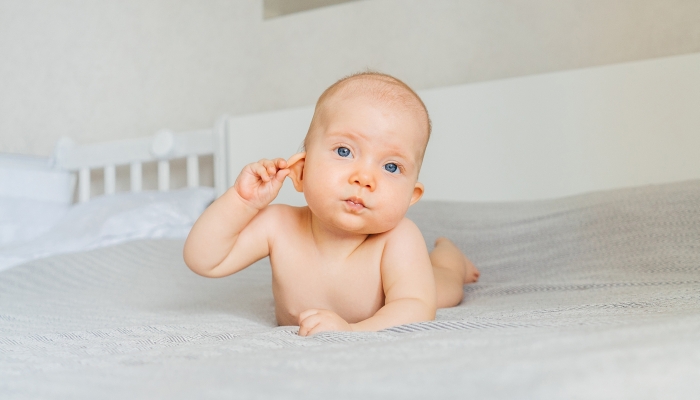 Child holds ear with hand.