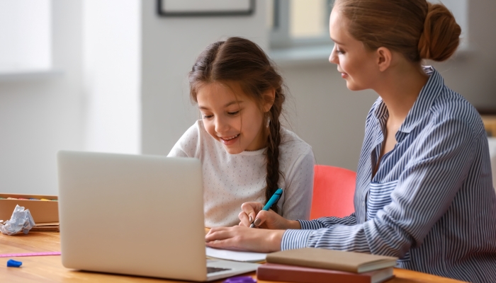 Cute girl with mother doing homework at home.