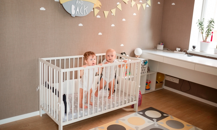 Cute little babies looking out of the bed in the room.