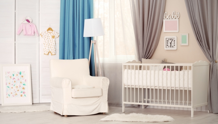 Interior of light cozy baby room with crib and bedding.