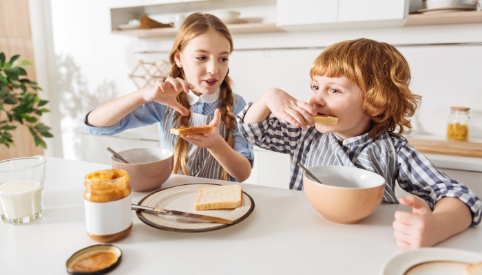 Lively cute girl making a sandwich for her brother.