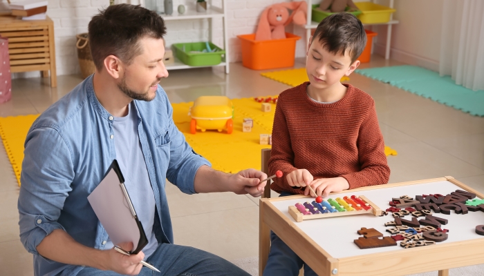 Male psychologist working with little boy in office. Autism concept.