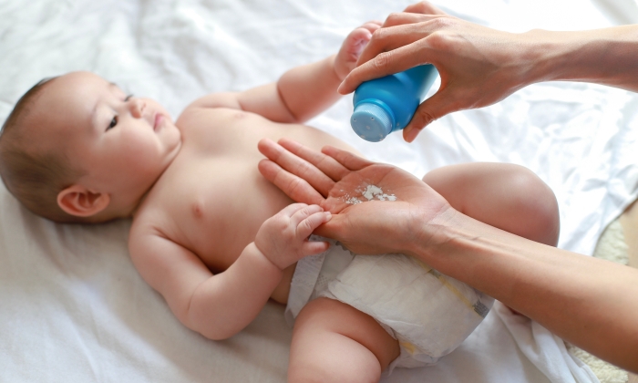 Mother applying talcum powder for her little baby boy.