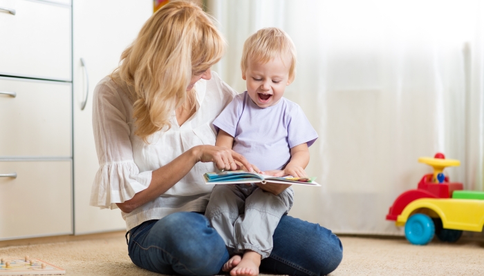 Mother looking at a book with her child son at home.