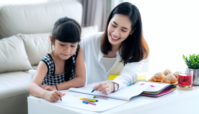 Mother teaches Asian preschool student do homework.